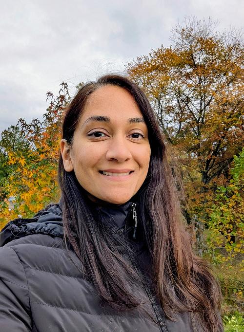 Smiling woman standing in a forest of vibrant autumn maple trees